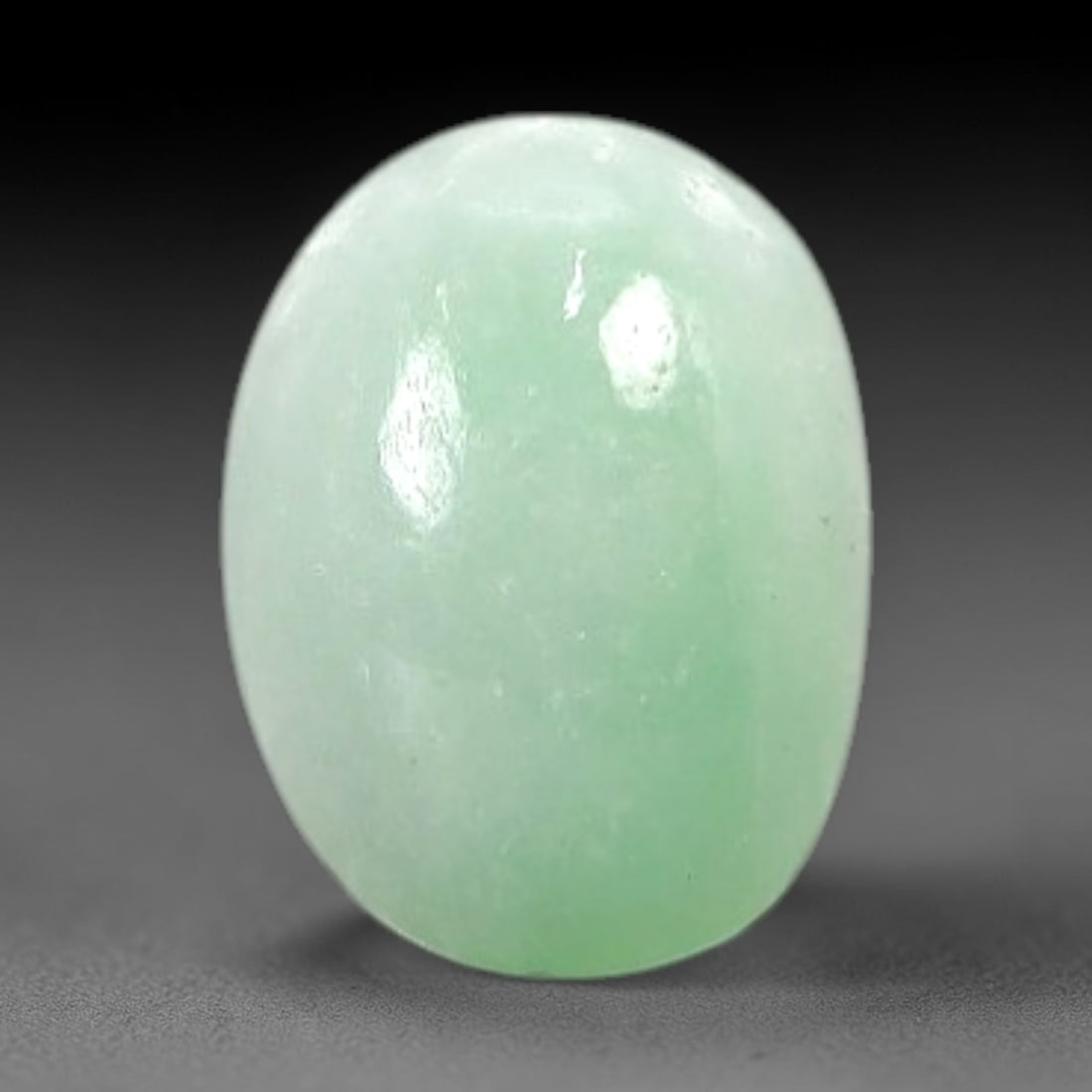 1.35 Carats Soft Mint Green Burmese Jadeite Jade Cabochon - Natural Loose Gemstone, 13AC: This oval Burmese jadeite jade cabochon exhibits a soft, uniform mint green hue, with a milky translucency that diffuses light evenly across its smooth, polished surface. The stone's even color distri