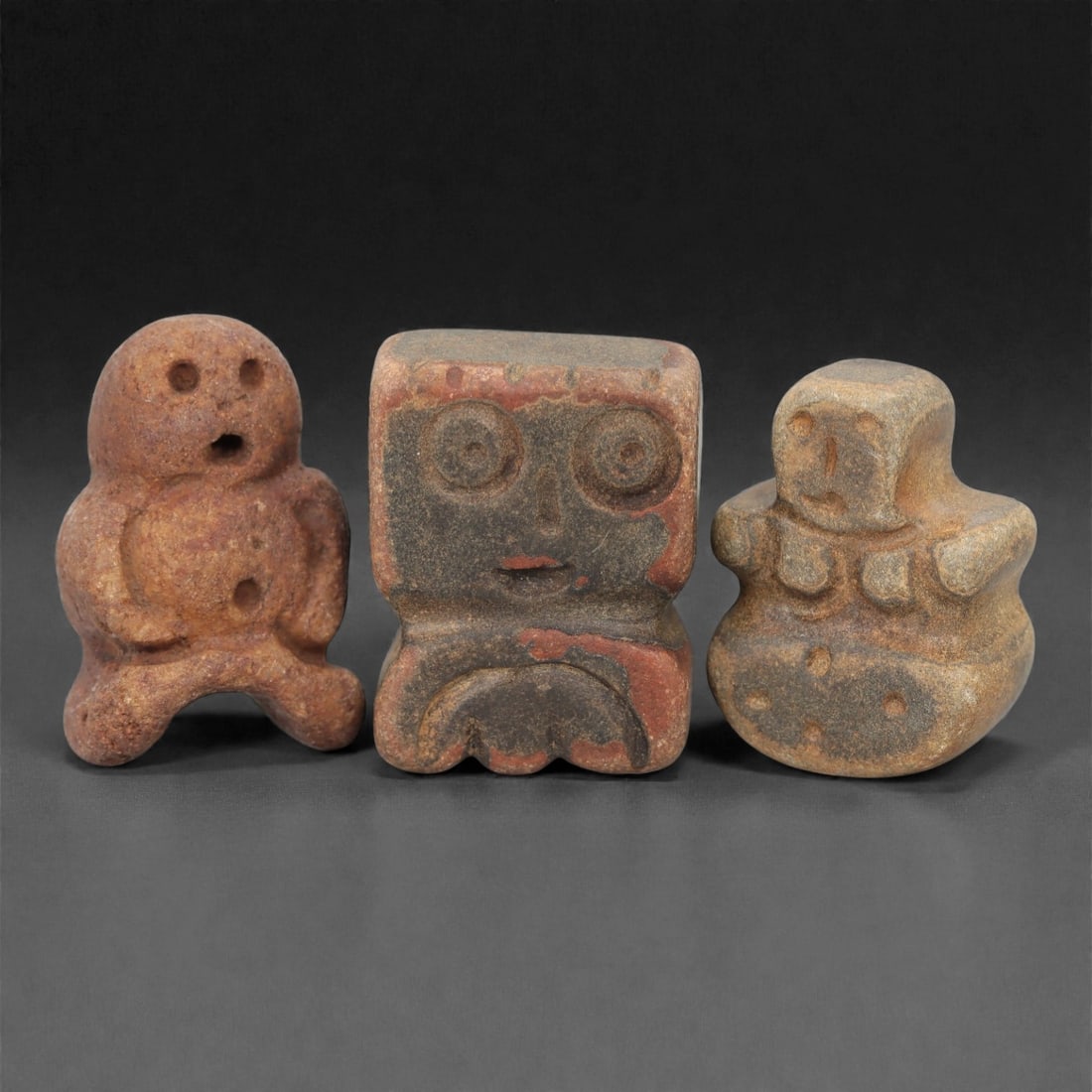 A Group of Three Ancient Near Eastern Stone Idols, 3rd-2nd Millennium BCE, 35FN: Comprising three idols, each is carved from stone with natural earthy tones ranging from terracotta brown to greyish-beige, with subtle mineral inclusions and surface patination consistent with age. T