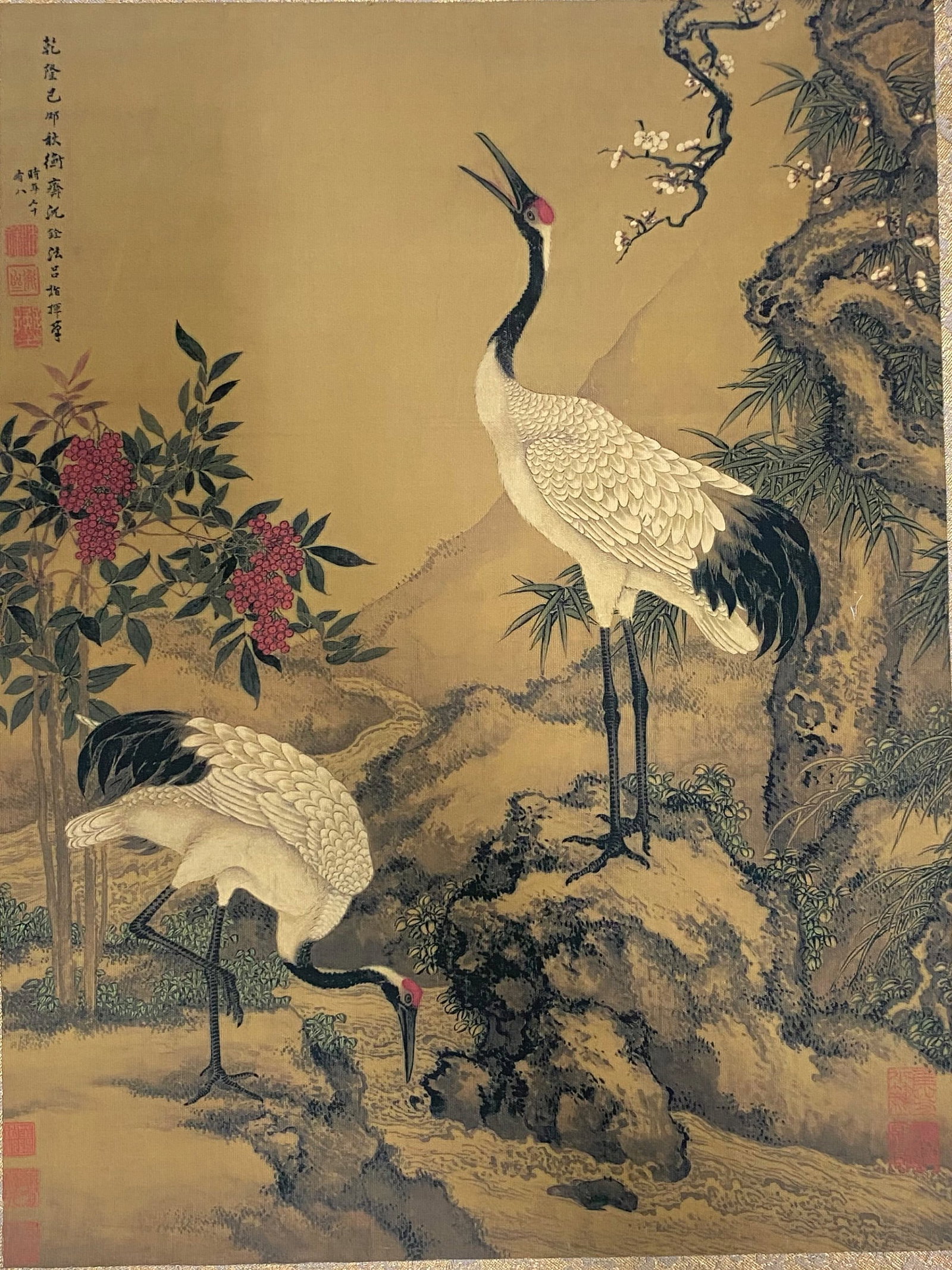 A Chinese Ink and Color Art Print, Cranes in a Landscape, 20th Century, 15FV: Printed on a warm, aged silk or paper ground, the composition depicts two red-crowned cranes in a literati landscape. One crane stands upright on a rocky outcrop with its neck extended and beak open, 