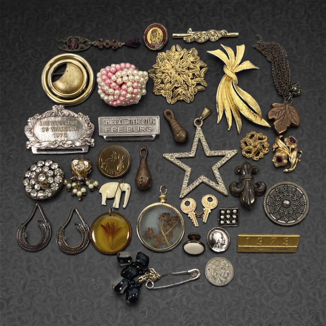 An Estate Lot of Thirty-One Charms, Pendants, and Brooches, Late 20th Century, 83FK, 83FK: The lot comprises thirty-one charms, pendants, and brooches, crafted from gilt and silver-toned alloy, with enamel, glass, faux pearl, resin, and dried botanical accents. The pieces include: a floral