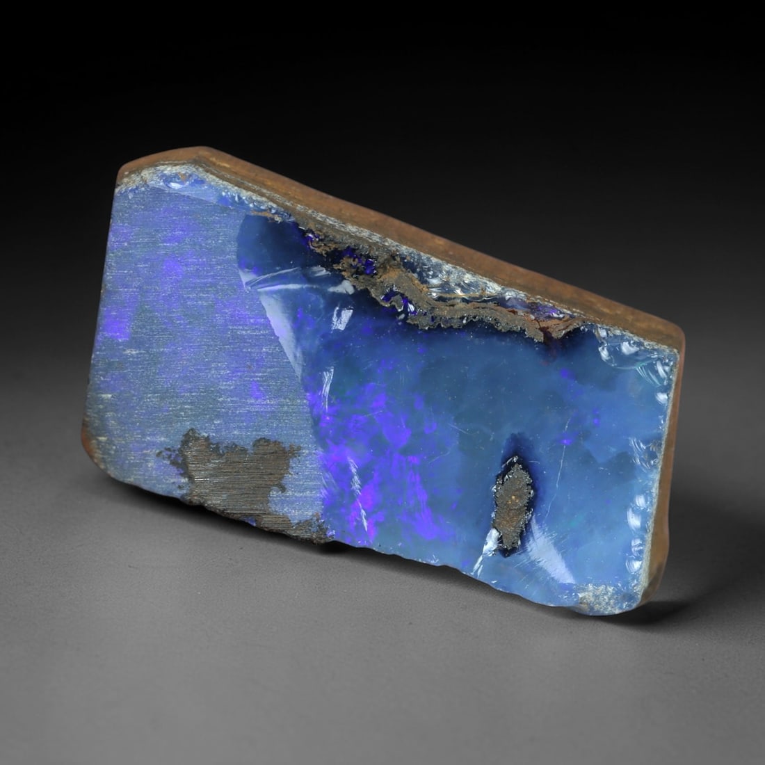 12.69 Carats Iridescent Deep Blue Purple Winton Opal Rough - Natural Australian 19x10mm, 88XM: This exceptional rough opal from Winton, Australia, captivates with a vivid play of color, where intense flashes of deep blue and regal purple swirl through a milky, translucent base. The natural, unp