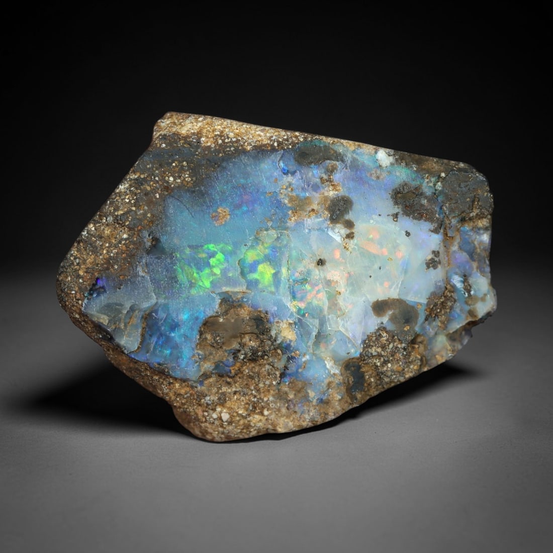 12.04 Carats Multicolor Iridescent Winton Opal Rough - Natural Australian Specimen 19x14mm, 84XM: This exceptional rough opal from Winton, Australia, dazzles with a kaleidoscopic play of color, where vivid flashes of electric green, celestial blue, and delicate peach-pink radiate from a milky, tra