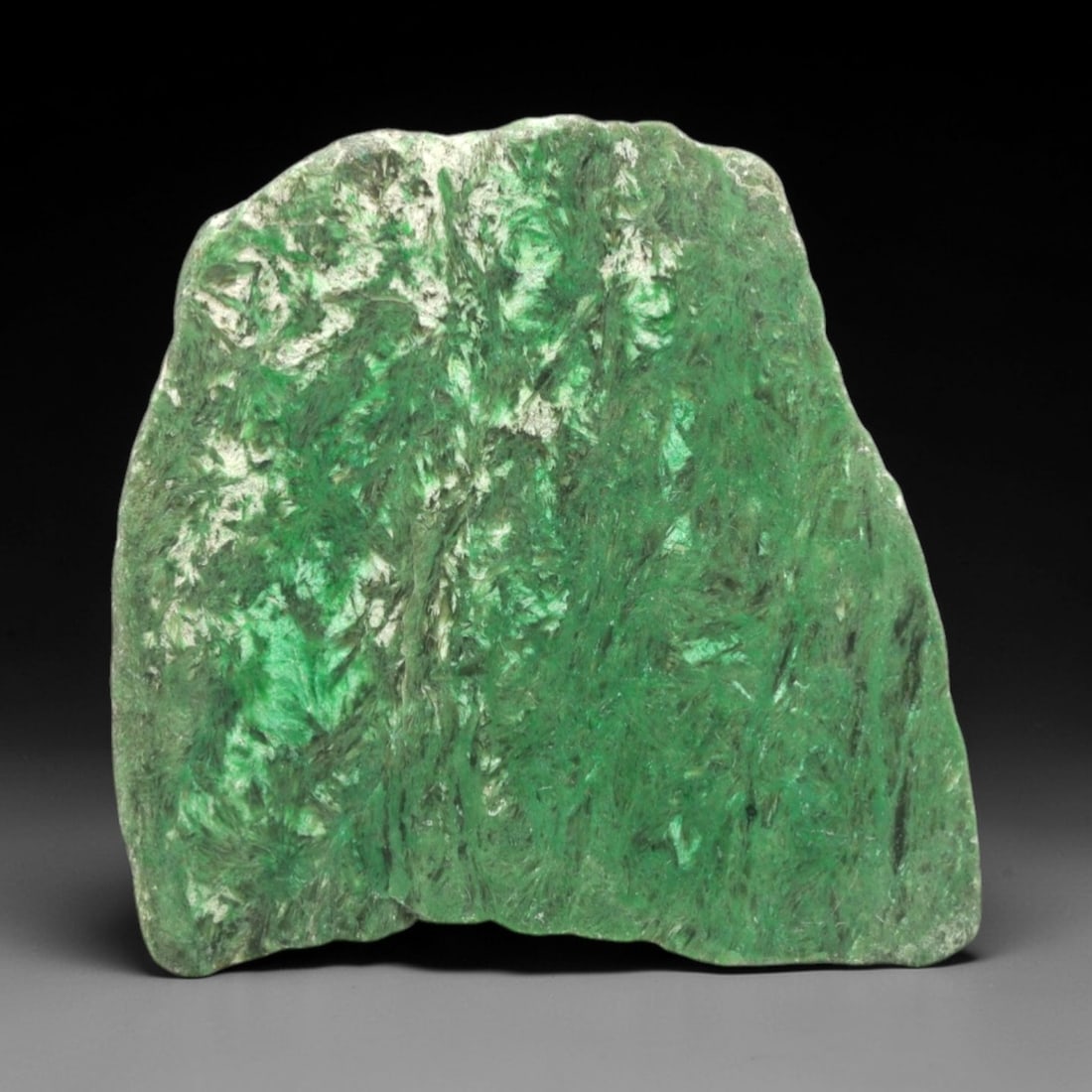 A Burmese Jadeite Jade Rough, 20th Century, 57FS: A piece of Burmese jadeite jade rough, with a vibrant green matrix and prominent white mineral inclusions. The rough is shaped as an irregular, angular form, with visible natural fractures and a parti