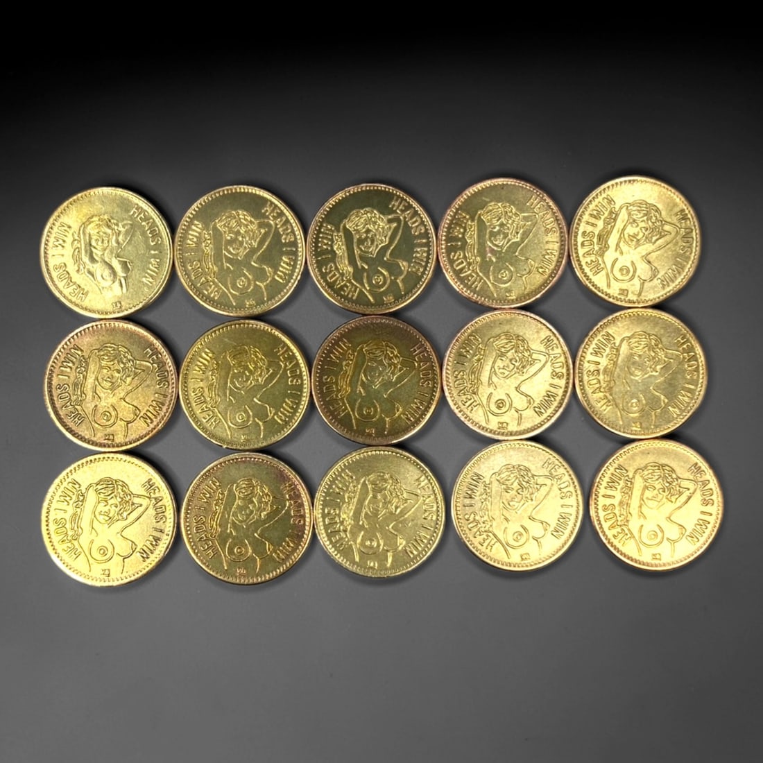 NOVELTY TOKENS: "Heads I Win, Tails You Lose" Erotic Flip Tokens - 15-Piece Set, 23mm, 7ZJ: This 15-piece set of brass and copper-nickel novelty tokens, each 23mm in diameter, features a dual-sided erotic design intended for adult novelty use. The obverse displays a pin-up style female figur
