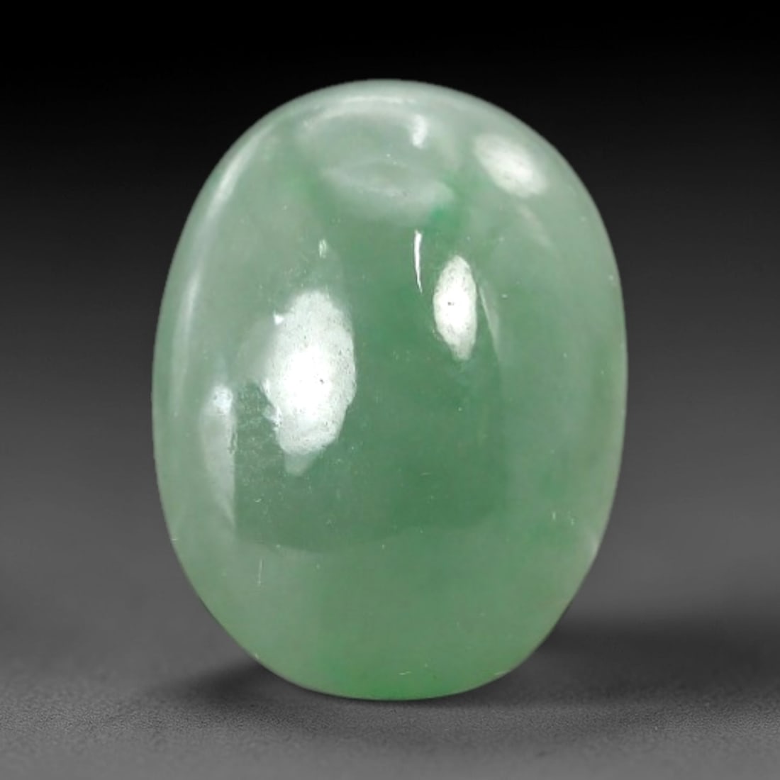 3.43 Carats Apple Green Jadeite Cabochon - Natural Burmese Stone, 72AB: This oval jadeite cabochon features a uniform apple green hue with a refined semi-translucent matrix that captures and diffuses light to produce a steady, understated luminescence. The domed cabochon