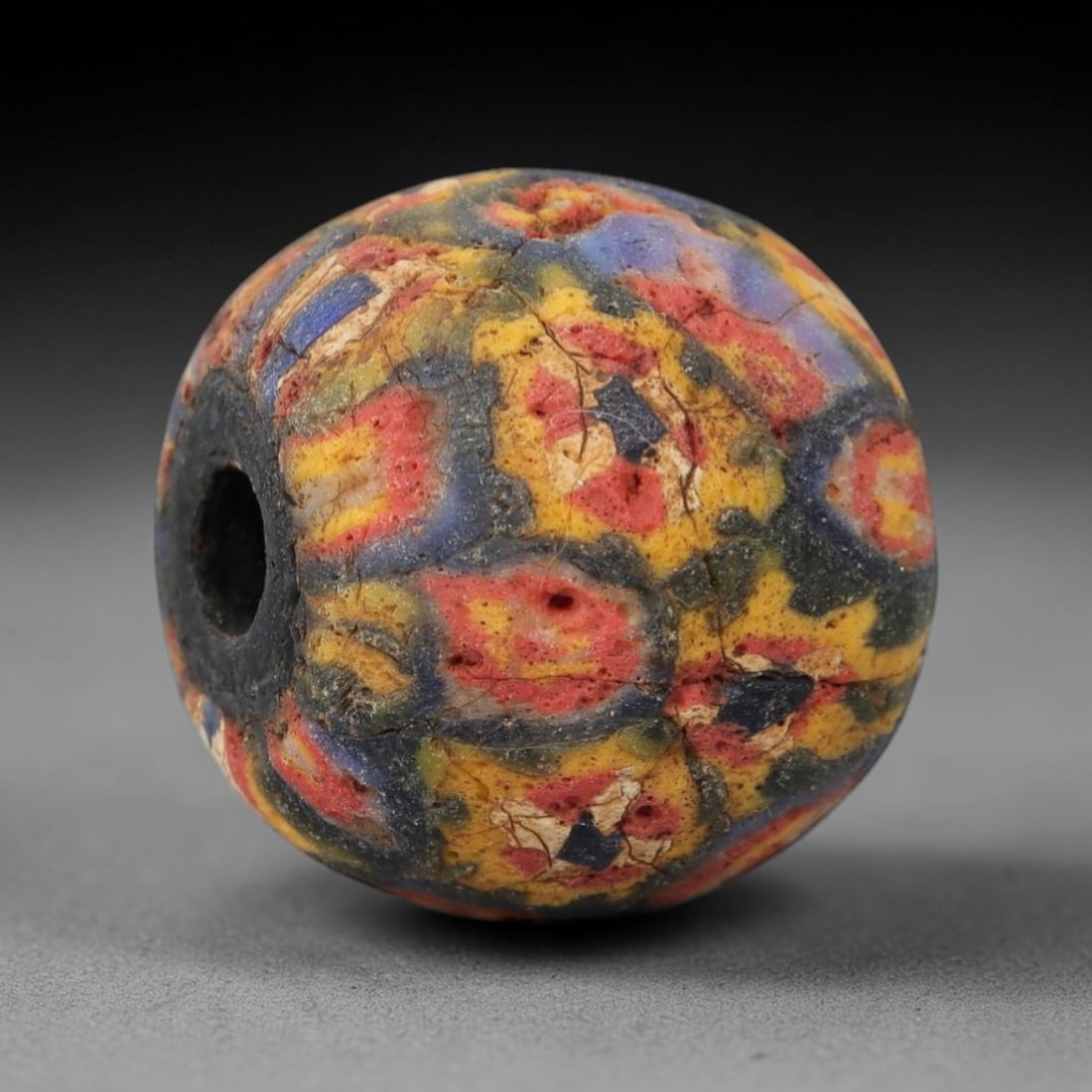 Ancient Glass Mosaic Bead - Roman Bead, 56ZM: This ancient bead is crafted from polychrome mosaic glass, formed using the millefiori technique characteristic of Roman glassworking traditions. The spherical form features a vibrant pattern of inter