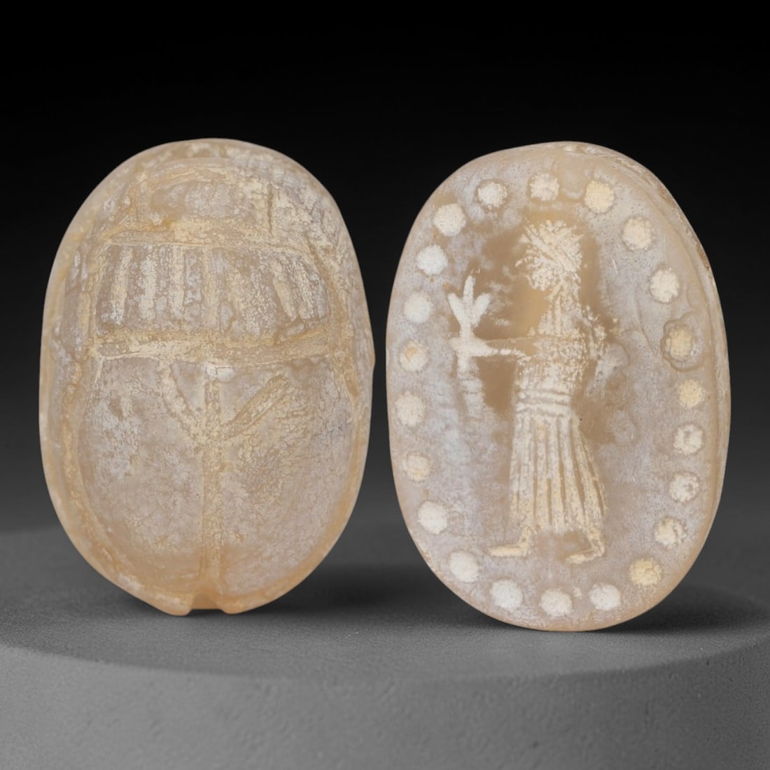 An Ancient Near Eastern Chalcedony Scarab Stamp Seal, 1st Millennium BCE, 98AC: Carved from translucent chalcedony with a pale, milky patina and subtle internal veining, the object is formed as an oval scarab seal. The dorsal side is modeled in low relief with a segmented carapac