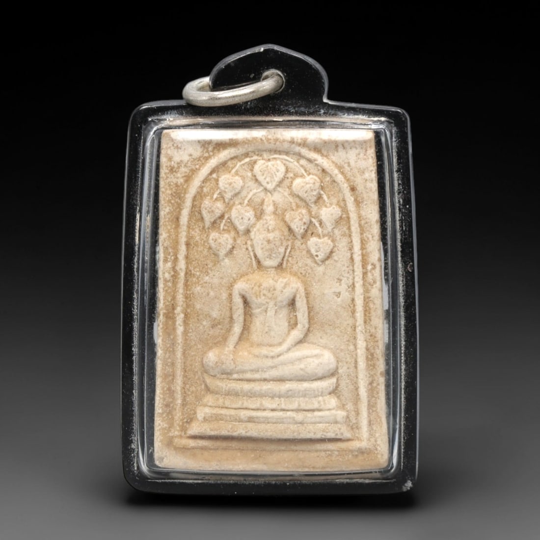 A Thai Phra Somdet Style Clay Amulet in Acrylic Case, 20th Century, 17ZK: This rectangular clay amulet (Phra Somdet) is encased in a modern, transparent acrylic protective housing with a black border and a metal suspension loop at the top for wear. The obverse features a ba