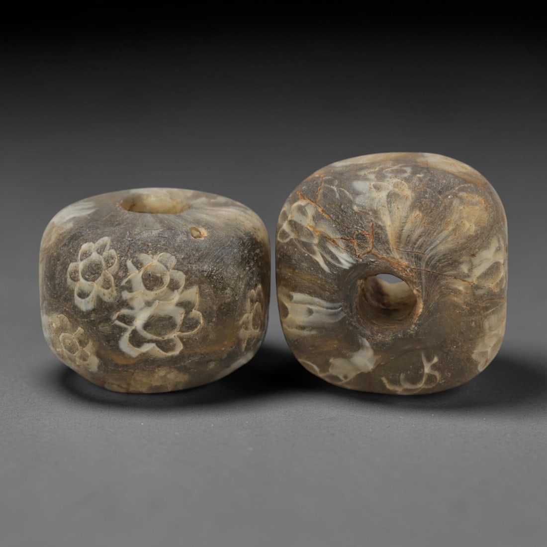 A Pair of Venetian Millefiori Glass Beads, 19th-20th Century, 63AD: Fabricated from translucent brownish glass with white inclusions, each bead is formed as a short cylinder with a central drilled perforation. The surface is decorated with characteristic millefiori ca