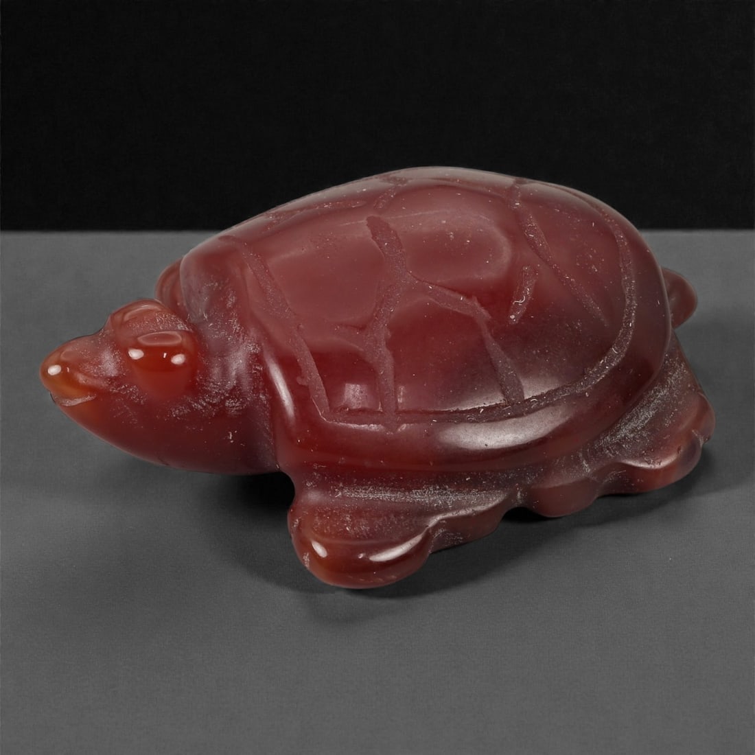 A Chinese Carnelian Tortoise Carving, 20th Century, 54YB: Carved from translucent reddish-brown carnelian with lighter clouding and natural tonal variation, the figure represents a tortoise shown recumbent with the head extended and the limbs folded beneath