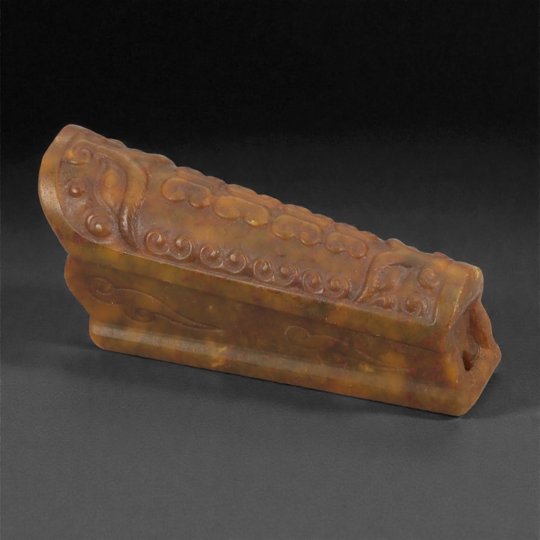 A Chinese Hetian Jade Coffin Amulet, 20th Century, 96YB: Carved from translucent brown-toned Hetian jade with areas of natural mottling and mineral variation, the object is worked as a stylized coffin-form amulet with a sloping lid and stepped base. The upp