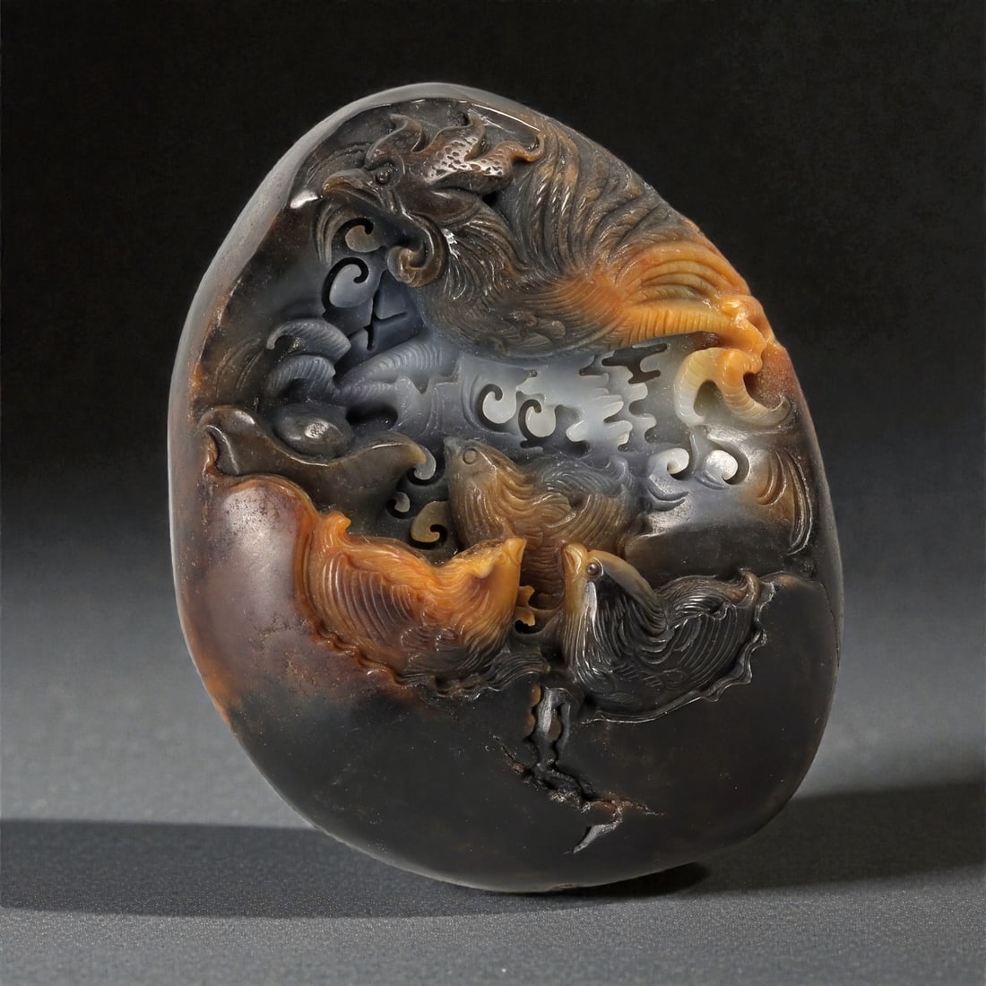 A Chinese Hetian Jade Phoenix and Bird Display Carving, 20th Century, 70FC: Carved from a single piece of dark-toned Hetian jade with dramatic russet and amber inclusions, this freestanding display carving is worked in high relief and openwork to depict a dynamic avian compos