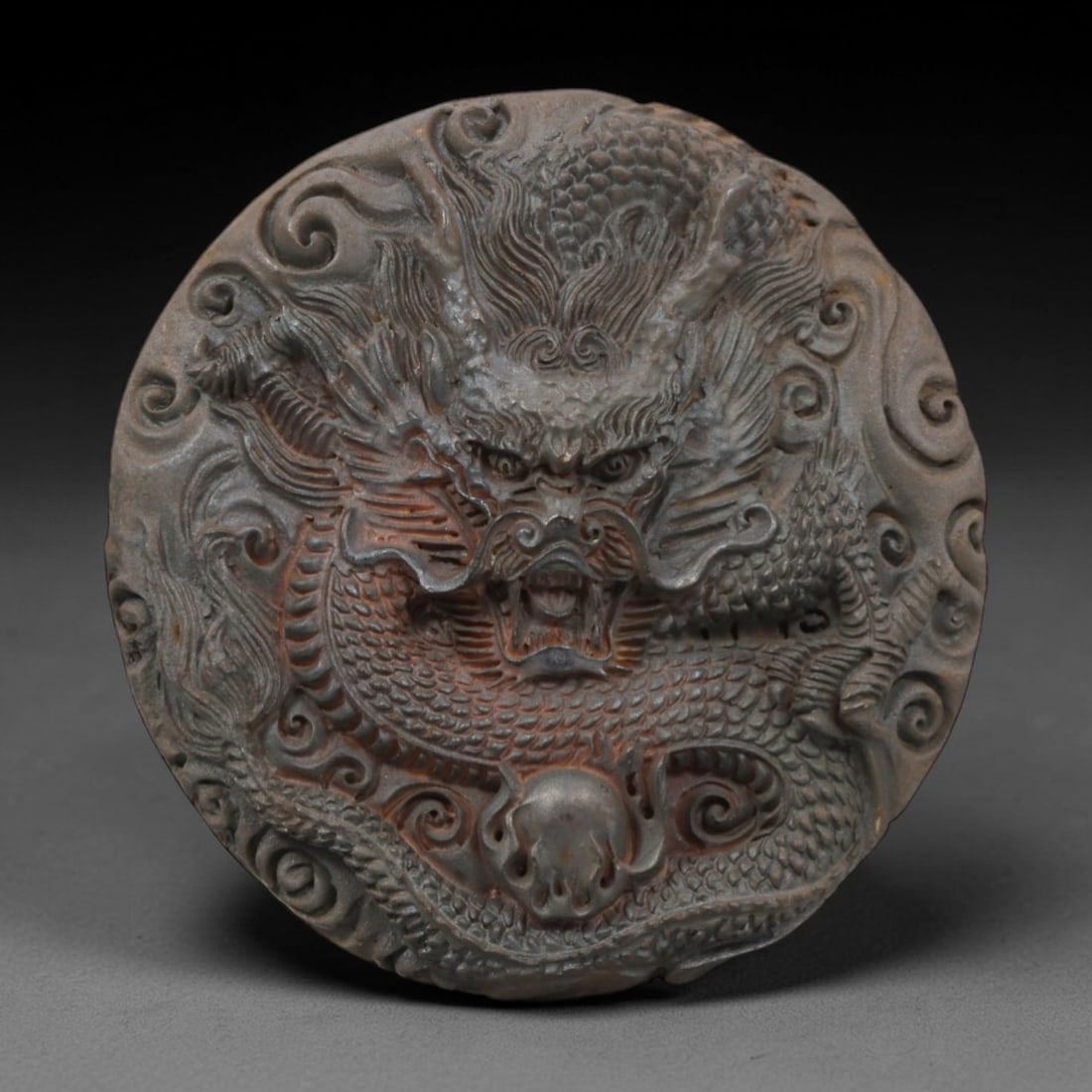 A Chinese Horn or Bone Dragon Pendant, 20th Century, 82FV: Carved from horn or bone with a naturally aged, patinated surface and subtle tonal variations, the pendant is circular in form, depicting a dragon in high relief. The dragon is rendered with detailed 