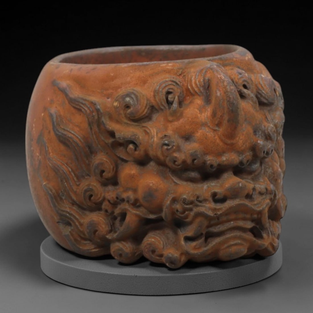 A Chinese Horn or Bone Carved Ring, 20th Century, 93FV: Carved from horn or bone with a warm, reddish-brown patina and subtle tonal variations, the ring is thick-walled and cylindrical in form. The exterior is deeply carved in high relief with a fierce myt