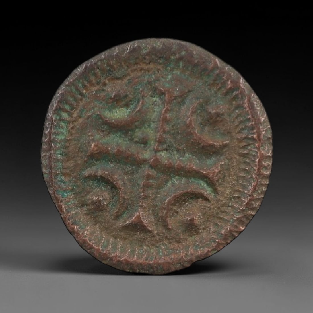 A Hungarian Bronze Denar of Bela II the Blind Coin, 1131-1141, 61FW: Cast from bronze with a naturally aged, patinated surface and prominent green verdigris, the coin is circular in form. The obverse features a cross potent with four crescent motifs, framed by a beaded