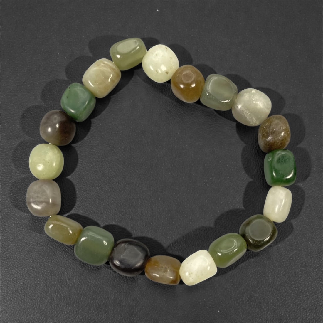 A Chinese Hetian Jade Beaded Bracelet, 20th Century, 41FJ: The bracelet is composed of a continuous strand of rounded rectangular beads carved from Hetian nephrite jade, each bead smoothly polished and exhibiting natural variation in color and translucency. T