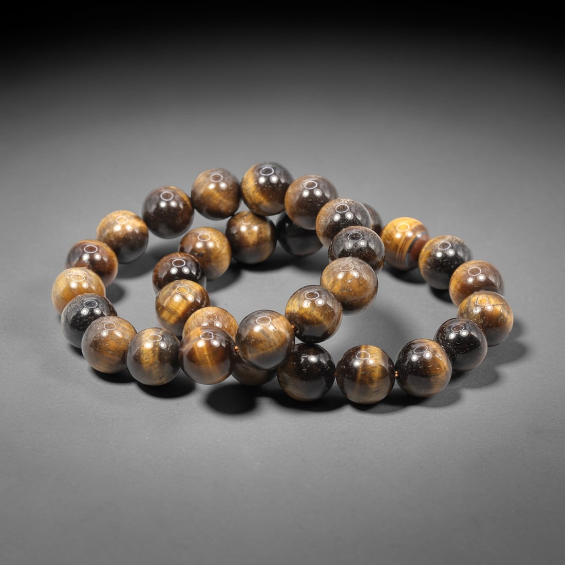 Two Tiger's Eye Bracelets, 20th Century, 87ZH: Comprising two bracelets, each strung with spherical tiger's eye beads of uniform diameter. The beads exhibit a rich spectrum of golden-brown to deep brown bodycolor, with prominent chatoyant bands of