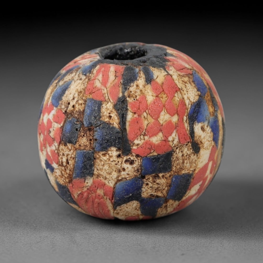 Ancient Glass Mosaic Bead - Roman Bead, 47ZM: This ancient bead is crafted from polychrome mosaic glass, formed using the millefiori technique characteristic of Roman glassworking traditions. The spherical form features a repeating checkerboard p