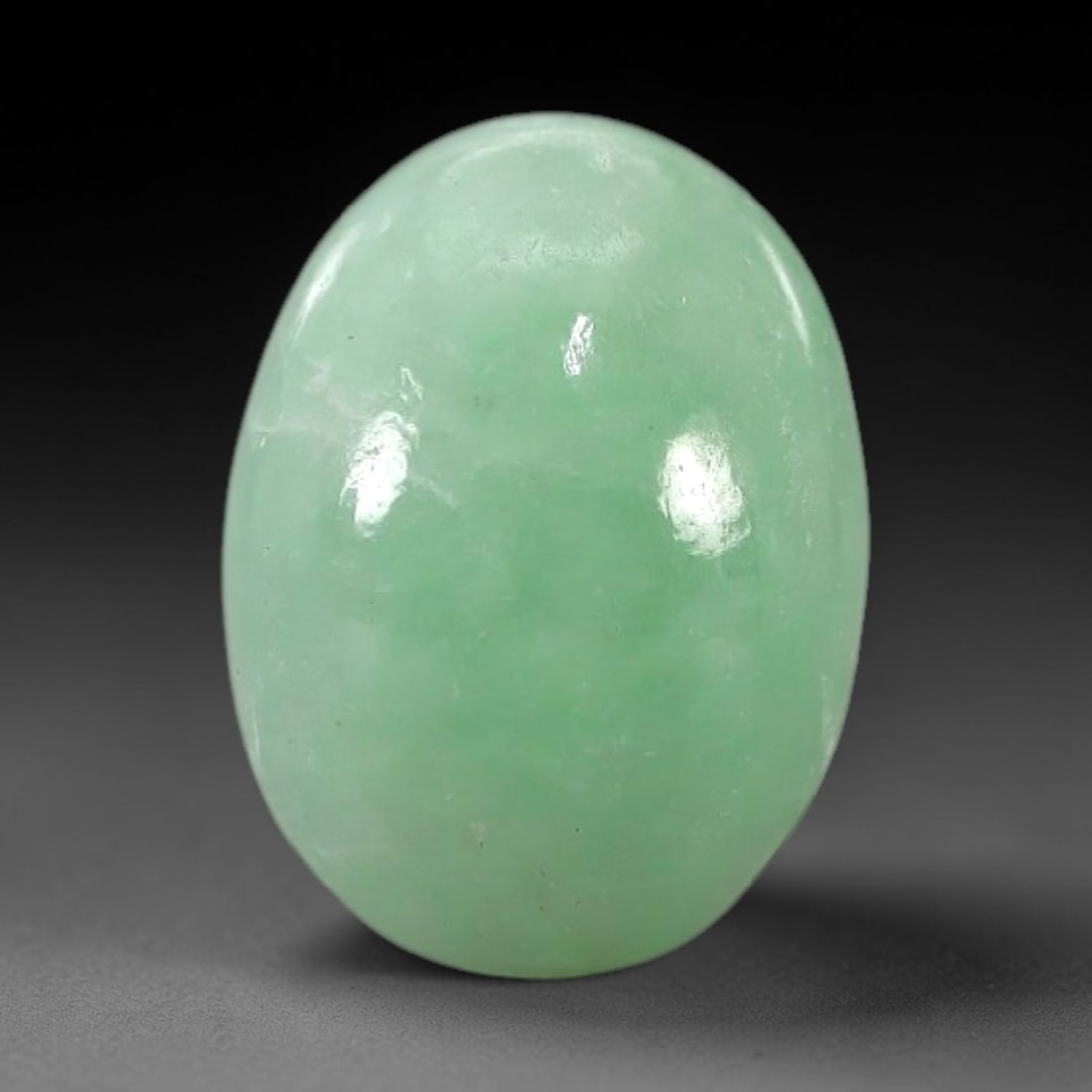3.38 Carats Apple Green Burmese Jadeite Jade Cabochon - Natural Loose Gemstone, 66XN: This singular Burmese jadeite jade cabochon presents a luminous apple green hue, soft and luminous with a translucent quality that allows light to filter gently through its smooth, domed surface. The