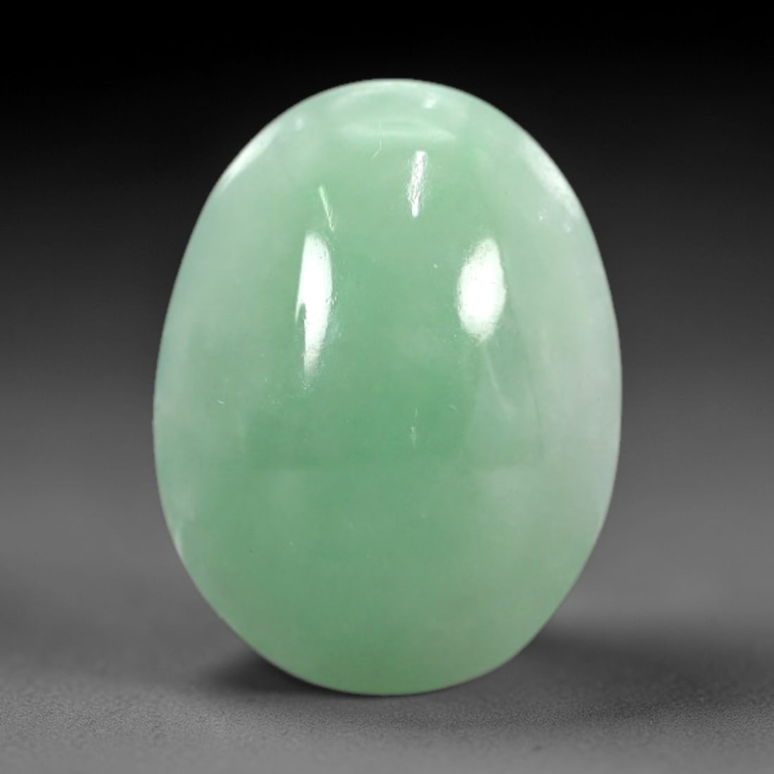 3.34 Carats Apple Green Burmese Jadeite Jade Cabochon - Natural Loose Gemstone, 56XN: This singular Burmese jadeite jade cabochon presents a luminous apple green hue, soft and luminous with a translucent quality that allows light to filter gently through its smooth, domed surface. The