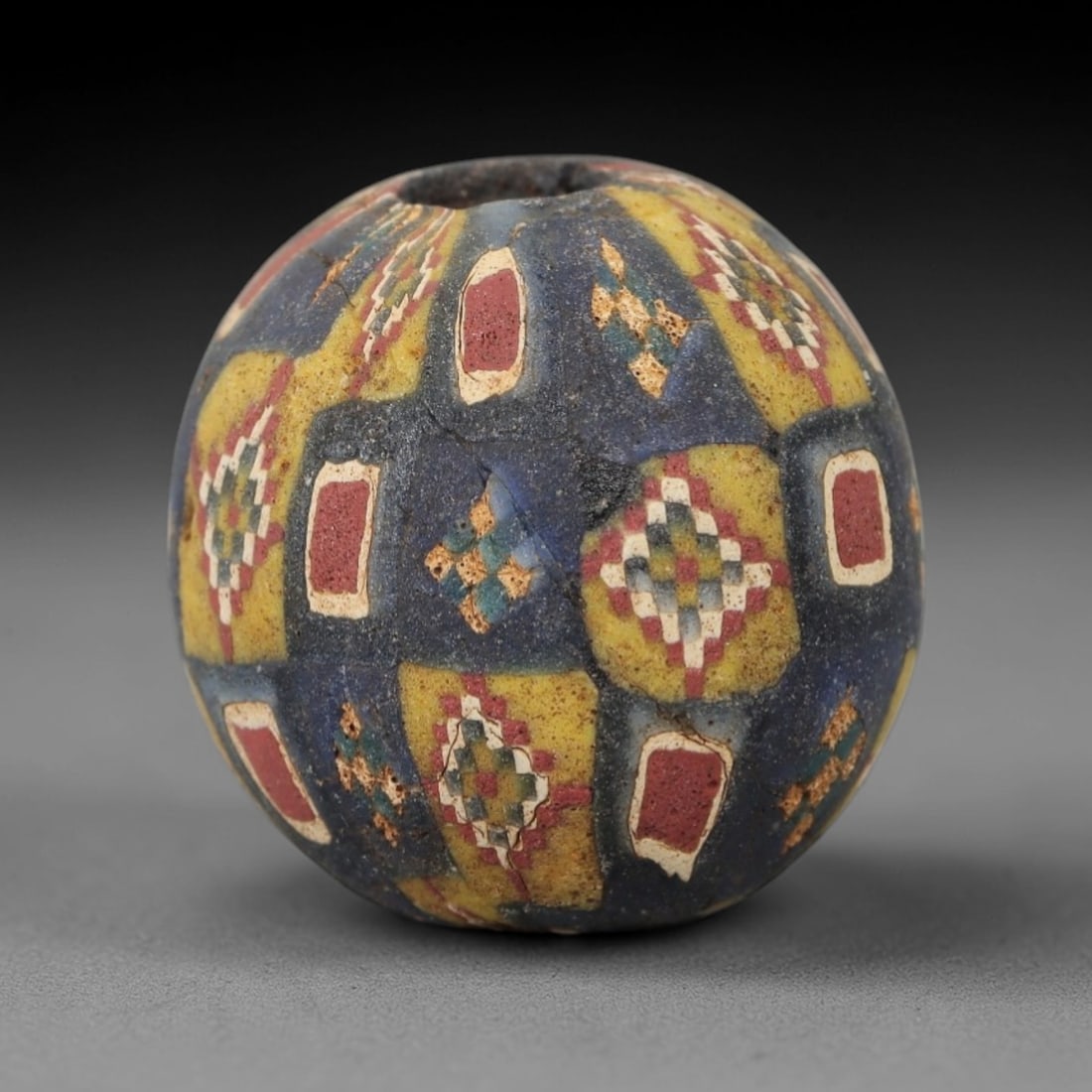Ancient Glass Mosaic Bead - Roman Bead, 53ZM: This ancient bead is crafted from polychrome mosaic glass, formed using the millefiori technique characteristic of Roman glassworking traditions. The spherical form features a repeating geometric patt