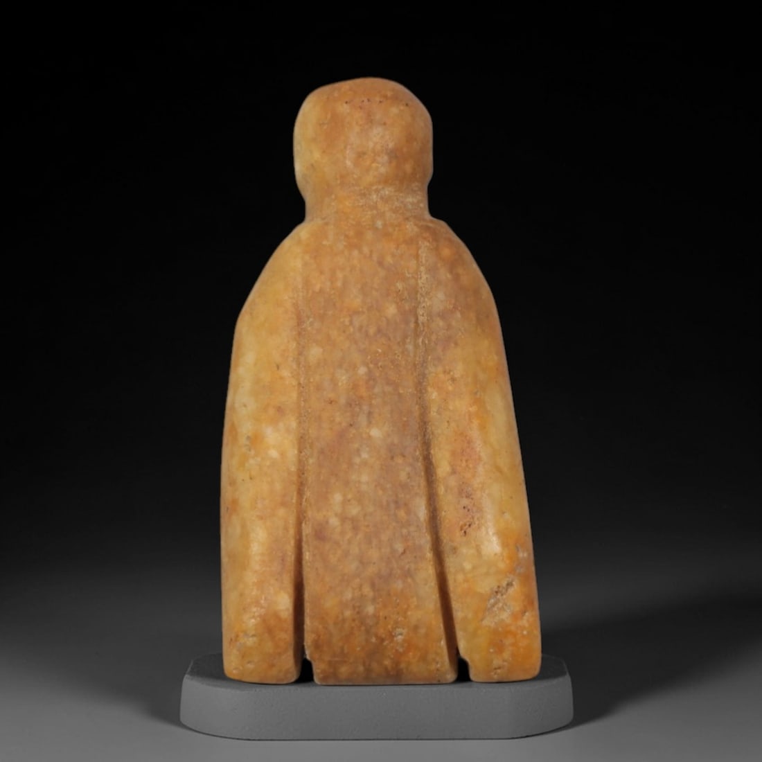 Ancient Yellow Stone Idol - Near Eastern Anthropomorphic Figurine, 79XP: Carved from warm, granular yellow stone, this miniature anthropomorphic idol features a simplified, stylized form with a rounded head and a broad, vertically segmented body. The design is minimalist a