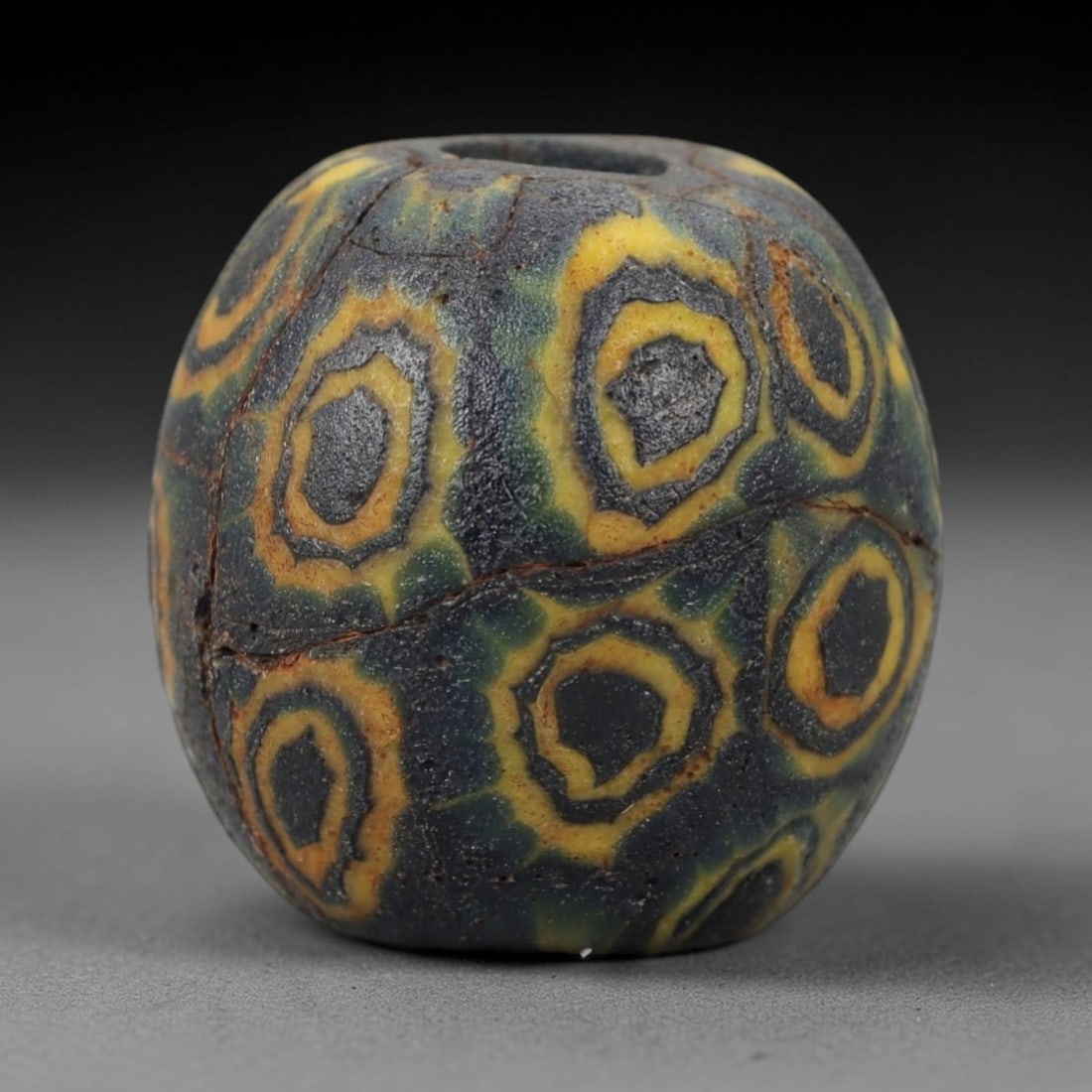 Ancient Glass Eye Bead - Islamic Mosaic Amulet, 39FW: Crafted from opaque dark blue glass with bright yellow concentric ring inclusions, this barrel-shaped bead employs the mosaic glass technique, where colored glass canes are fused and sliced to form re