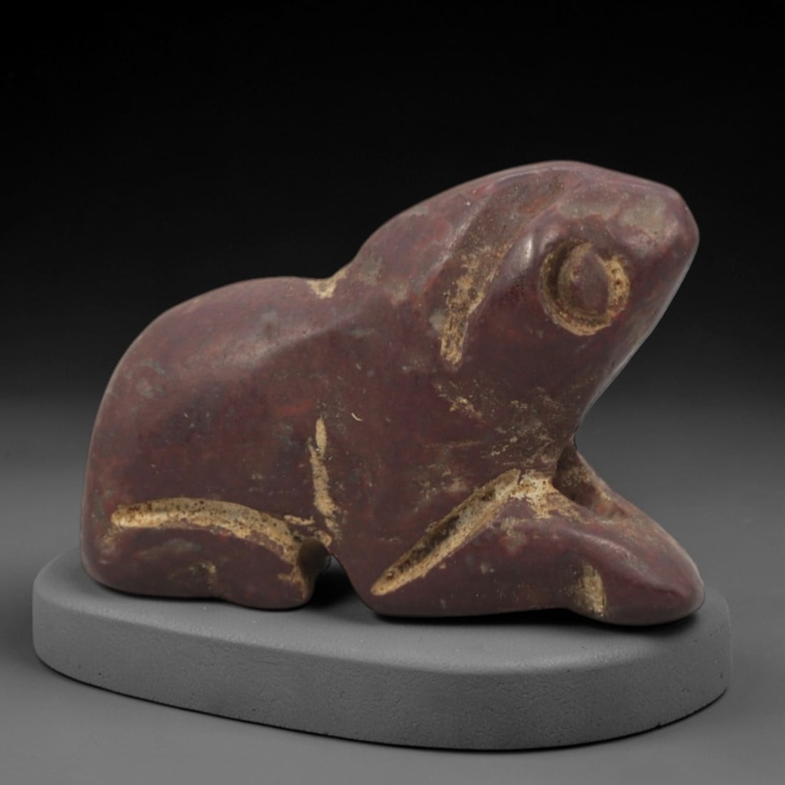 Ancient Red Stone Feline - Near Eastern Zoomorphic Figurine, 69XP: Carved from dense, deep red stone, this miniature zoomorphic figurine depicts a stylized recumbent feline, likely a lion or panther, a powerful motif in ancient Near Eastern iconography symbolizing ro