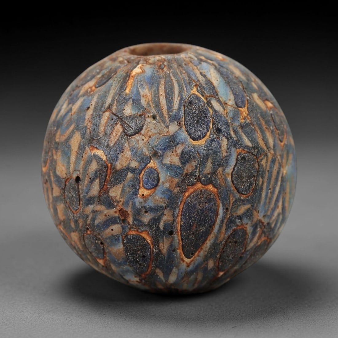 Ancient Glass Mosaic Bead - Roman Amulet, 45FW: Crafted from fused translucent blue and cream glass canes with dark blue inclusions, this spherical bead employs the mosaic glass technique, where colored glass elements are fused and sliced to form a
