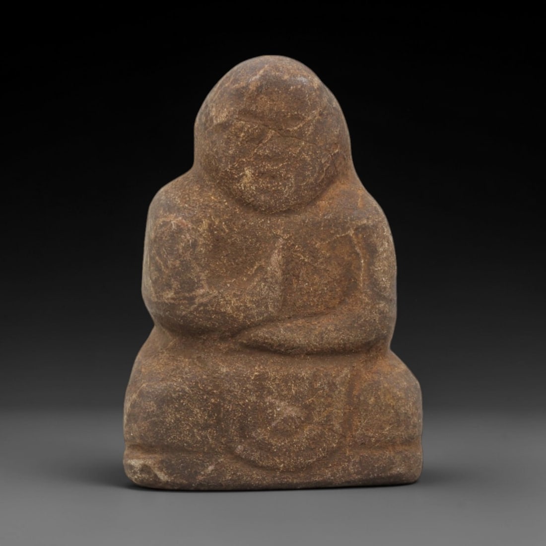 Ancient Style Stone Monk - Japanese Edo Figurine, 91FW: Carved from granular brown stone, this seated figure depicts an Edo-period monk in a meditative cross-legged posture. The figure features a rounded head with simplified facial features, including indi