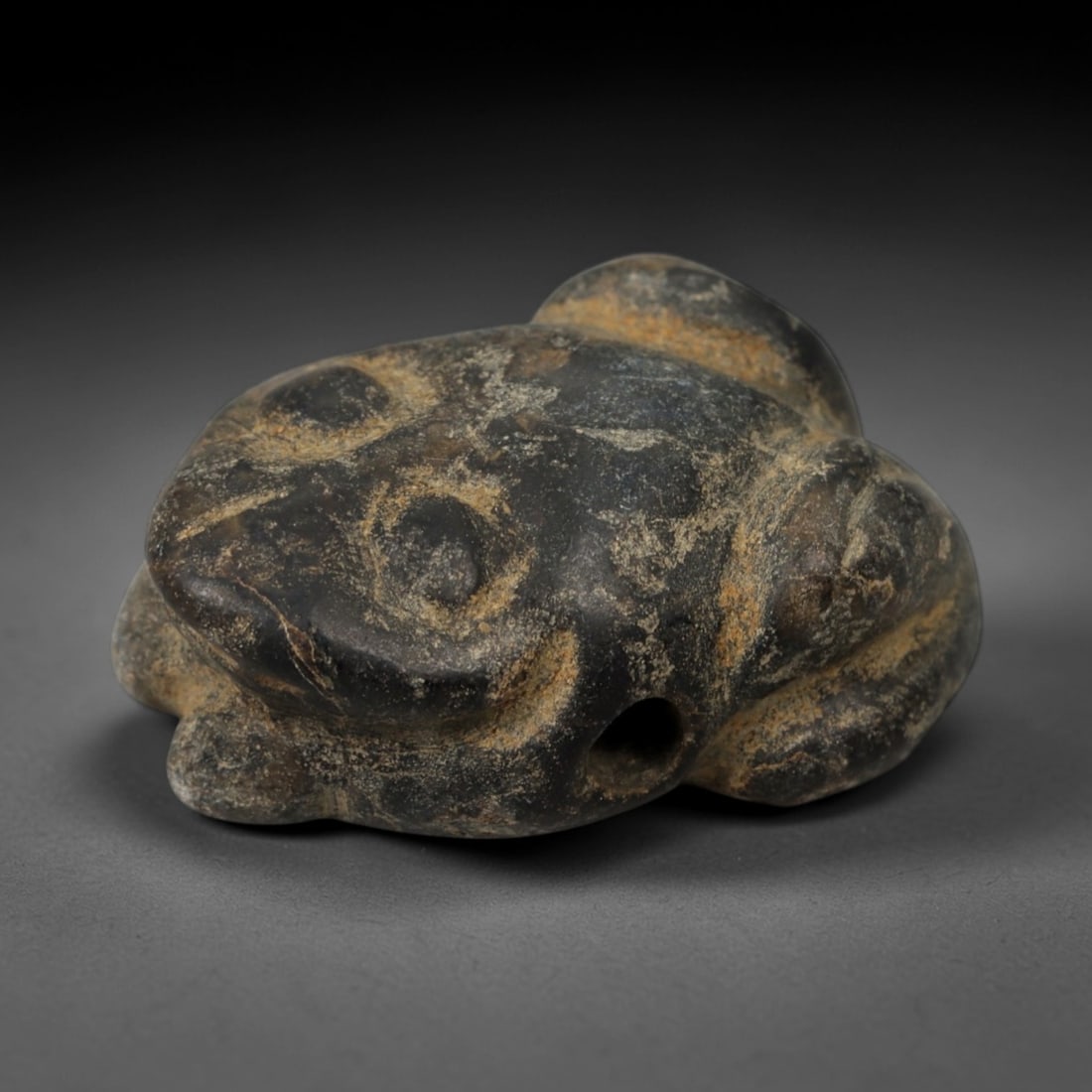 Ancient Stone Frog Amulet - Near Eastern Relic, 1AE: Carved from dark stone with earthy mineral encrustations, this amulet takes the form of a squatting frog, a motif associated with water and fertility symbolism in ancient Near Eastern iconography. The