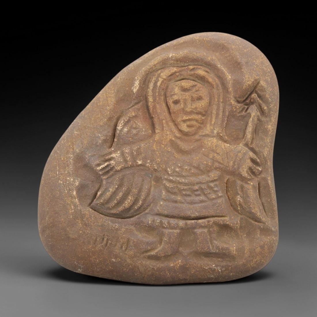 Ancient Stone Christian Figure - European Religious Idol, 36FX: Carved from a compact block of brown granular stone, this relief carving depicts a standing Christian figure in a devotional stance. The figure is adorned with a hooded headdress and a detailed robe w