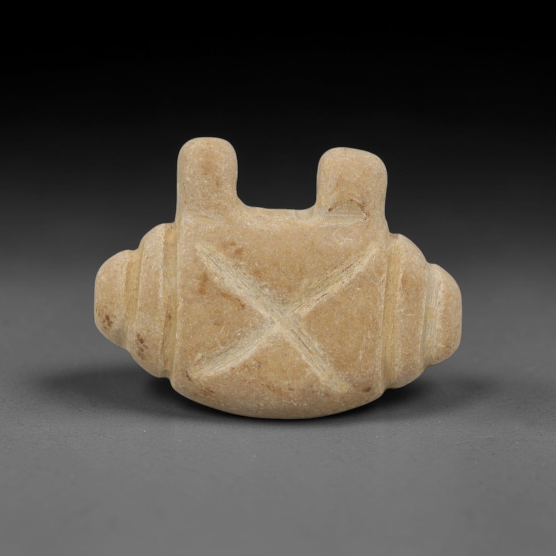 Ancient Tan Stone Cross-Emblem Pendant - Near Eastern Ritual Amulet, 6XQ: Carved from a smooth, warm tan stone with subtle brown mineral inclusions, this miniature pendant features a highly stylized geometric form, a distinctive motif in ancient Near Eastern ritual art. The