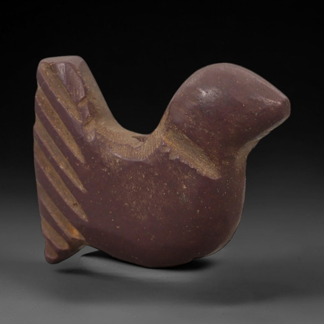 Ancient Purple Stone Bird Amulet - Near Eastern Figurine, 98AD: Carved from rich purple stone with fine granular texture, this amulet depicts a stylized bird in a compact, angular form. The creature is rendered with a rounded head, simplified body contours, and in