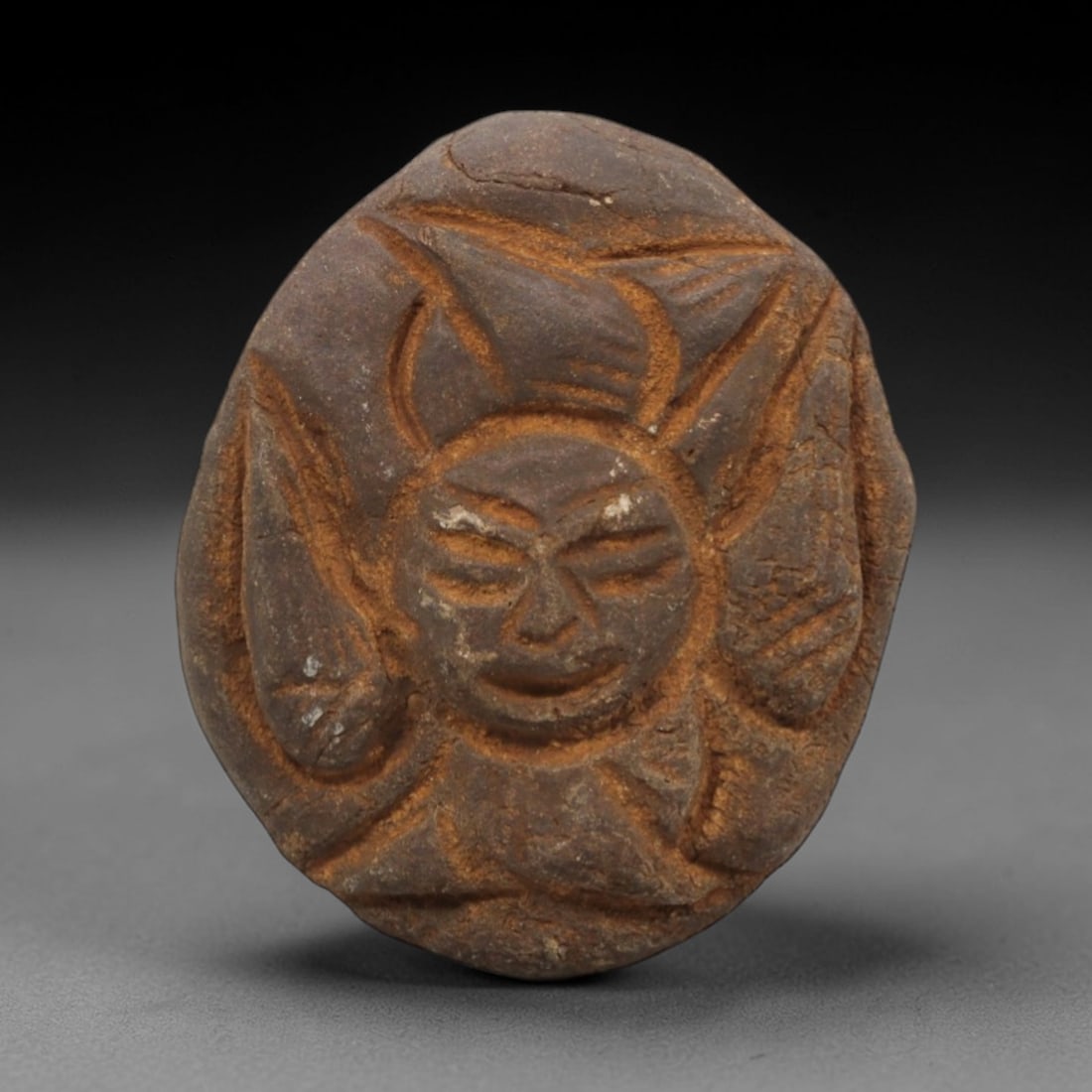 Ancient Stone Christian Sun Face - Religious Artifact, 21FX: Carved from a dense, earthy-brown stone with a weathered patina, this artifact depicts a Christian-themed sun face with a central anthropomorphic visage featuring closed eyes, a defined nose, and a ca
