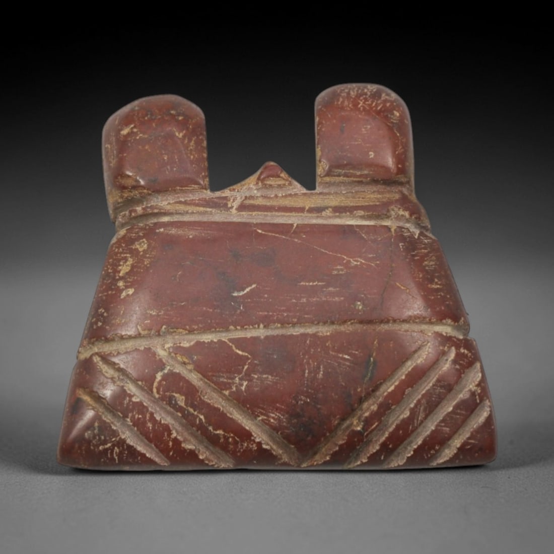 Ancient Red Stone Amulet - Near Eastern Twin-Horned Pendant, 86XP: Carved from rich, deep red stone, this amulet features a trapezoidal form with two raised, rounded horn-like protrusions at the apex, a distinctive iconographic element in ancient Near Eastern ritual