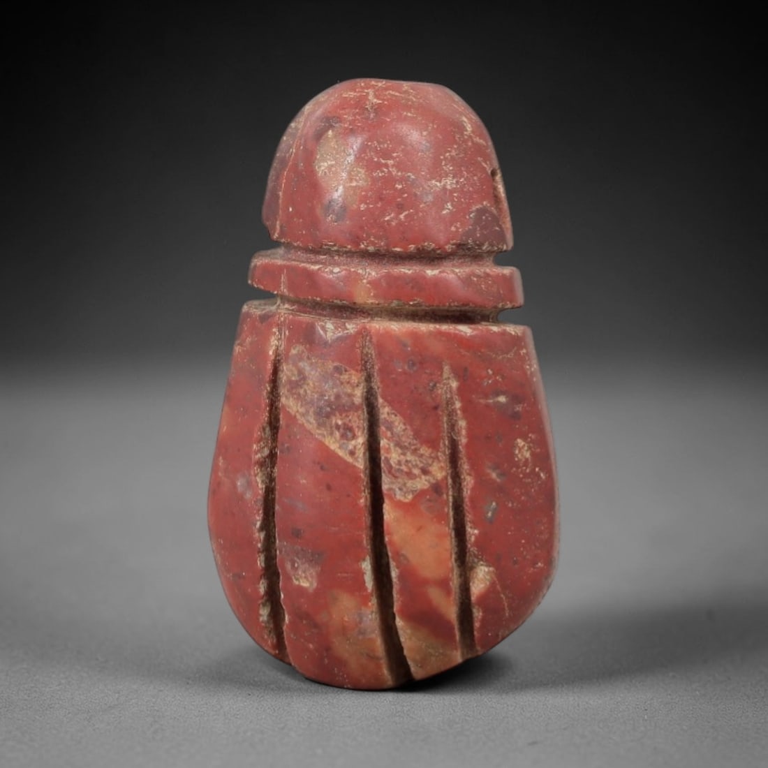 Ancient Stone Fly Amulet - Near Eastern Ritual Figurine, 19AG: This amulet is carved from a single piece of rich red stone, exhibiting a granular texture with subtle ochre patina and natural mineral inclusions across its surface. The form is a stylized fly, featu