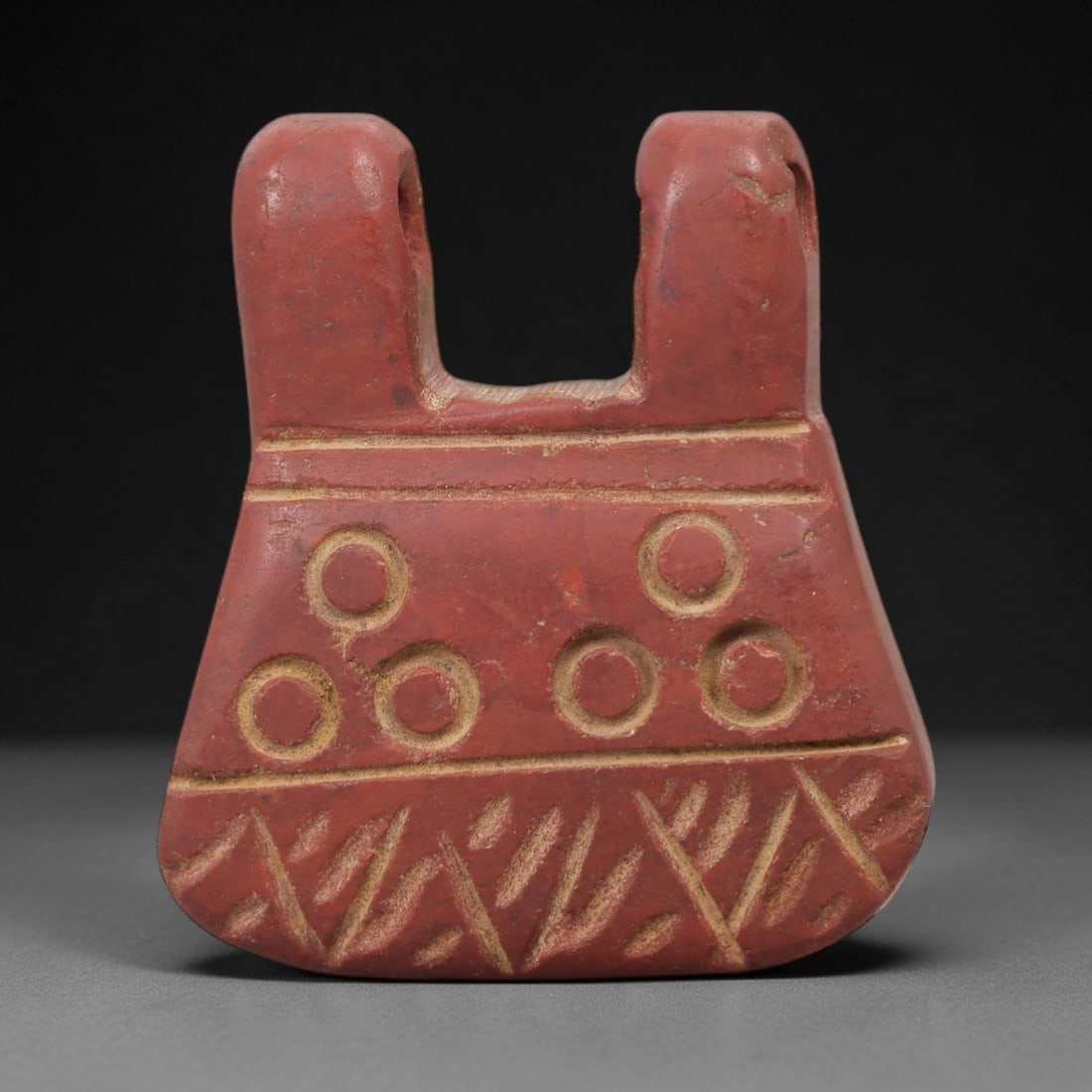 Ancient Egyptian Stone Amulet - Geometric Carved Pendant, 42AE: Carved from reddish-brown stone, this ancient Egyptian amulet features a rectangular form with a suspension loop at the top and a series of evenly spaced circular incisions along its length, a motif t