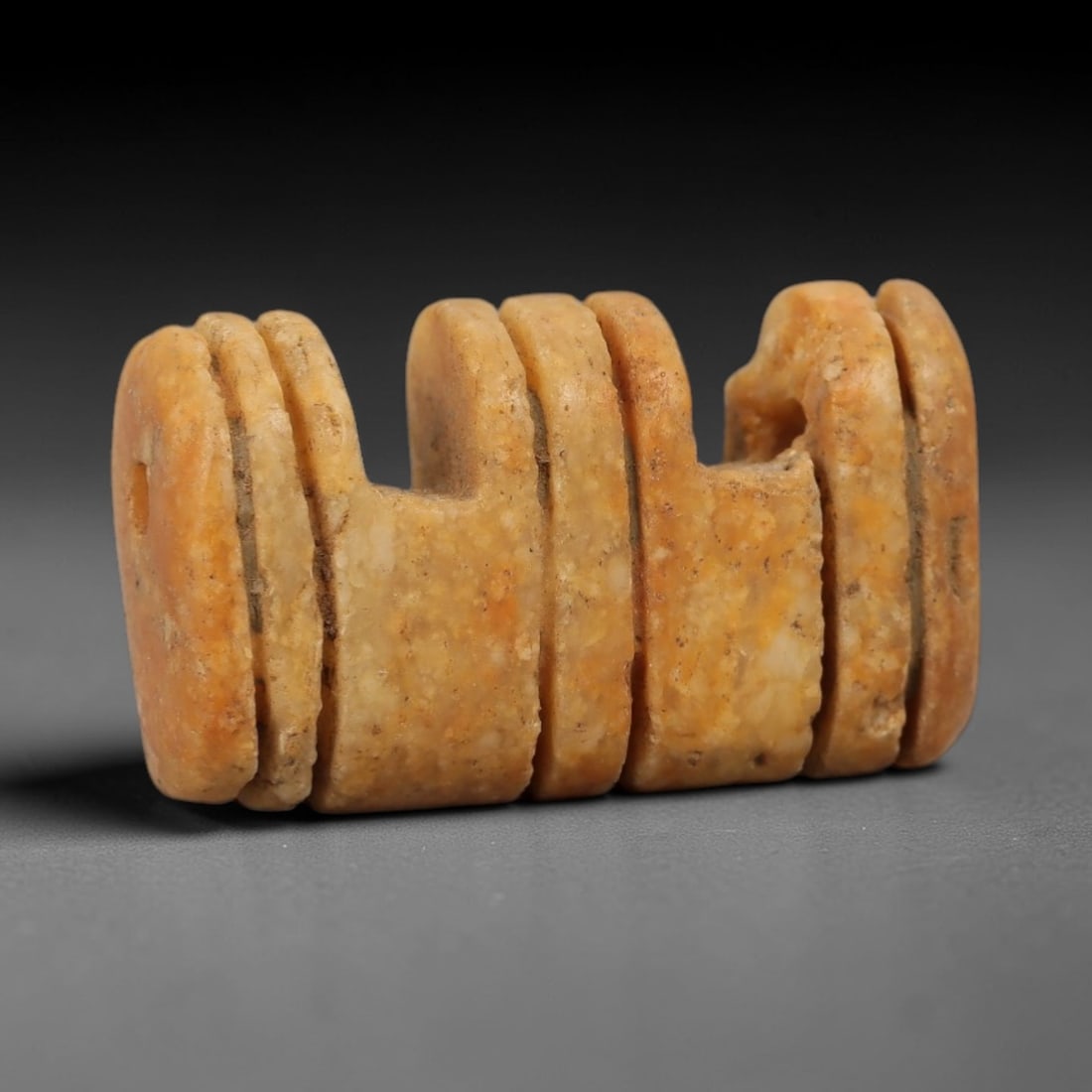 Ancient Stone Multi-Loop Amulet - Near Eastern Pendant, 44AG: This amulet is carved from a pale orange-tan stone with a granular texture and weathered, earthy patina. The form is a rectangular block with multiple vertical U-shaped notches cut into the upper edge