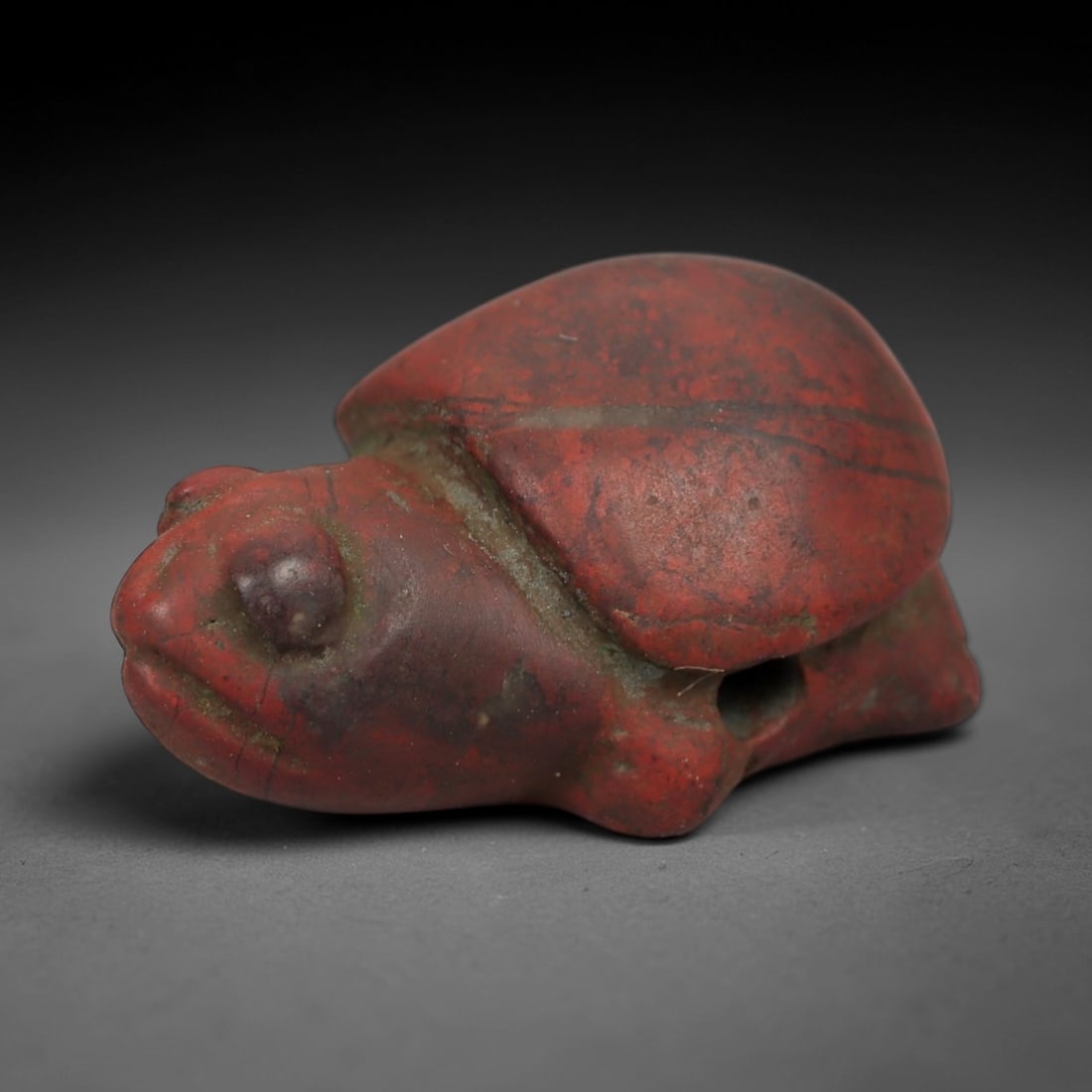 Ancient Stone Turtle Amulet - Near Eastern Ritual Figurine, 32AG: This amulet is carved from a single piece of rich red stone, exhibiting a fine-grained texture with subtle earthy veining and a warm matte patina across its surface. The form is a stylized turtle, fea