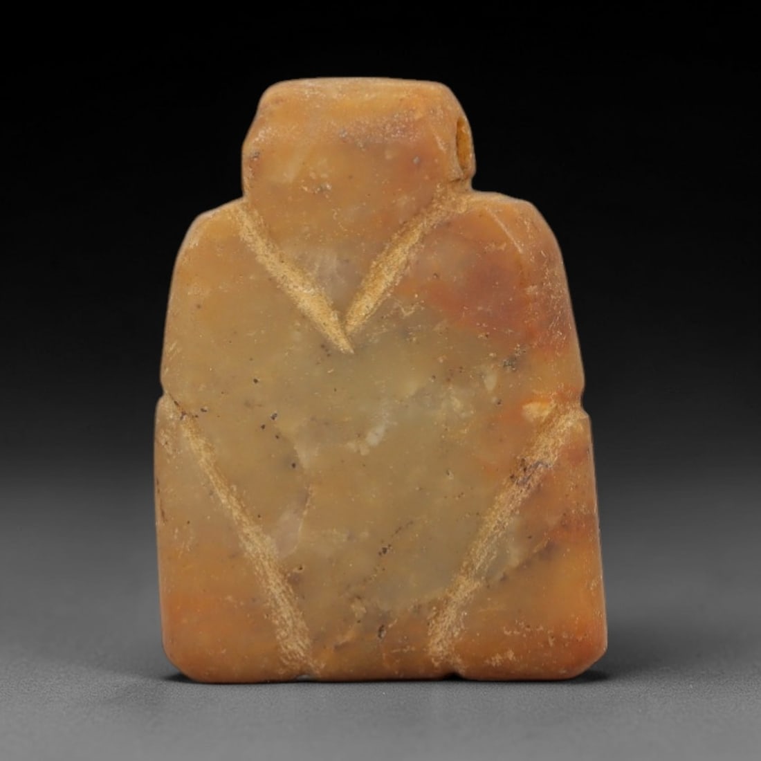 Ancient Stone Tyet Amulet - Egyptian Carved Pendant, 69AG: This amulet is carved from a pale yellowish-tan stone with a warm, earthy patina and subtle surface weathering. The form is a stylized Tyet (Knot of Isis) amulet, defined by a rectangular upper suspen