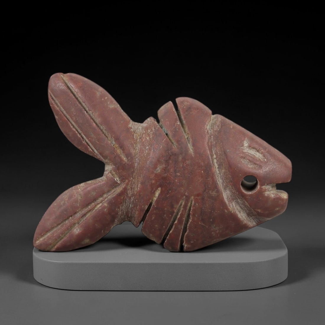 Ancient Egyptian Stone Fish Amulet - Geometric Carved Pendant, 66AE: Carved from stone, this ancient Egyptian fish amulet features a stylized fish form with geometric line patterns on the body, a common motif in Egyptian amulets for protection and good fortune. The com