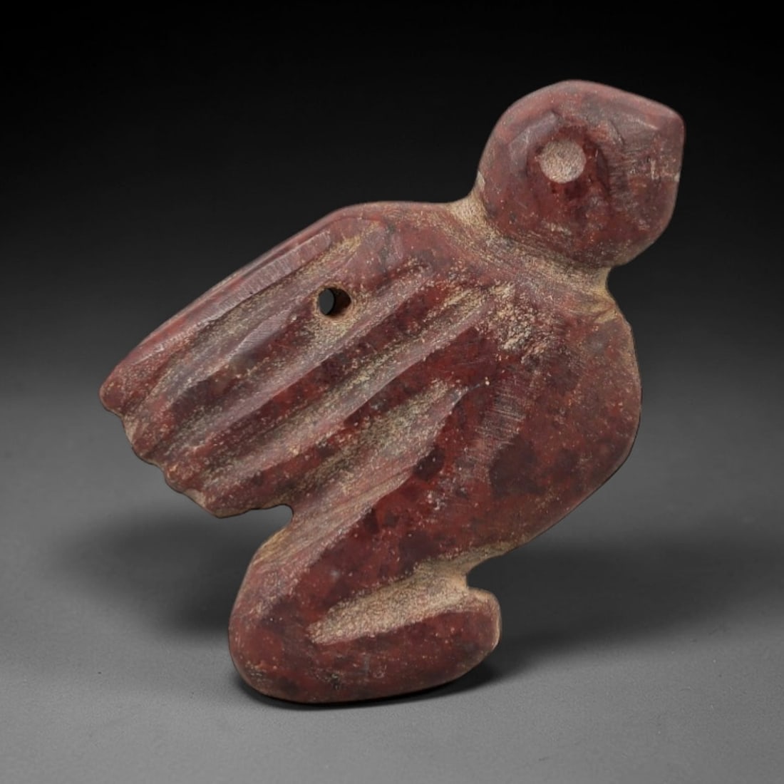 Ancient Egyptian Stone Bird Amulet - Geometric Wing Carving, 56AG: Carved from stone, this ancient Egyptian bird amulet features a stylized avian form with geometrically incised wing details, typical of protective amulets from the Late Period (c. 664-332 BCE). The si