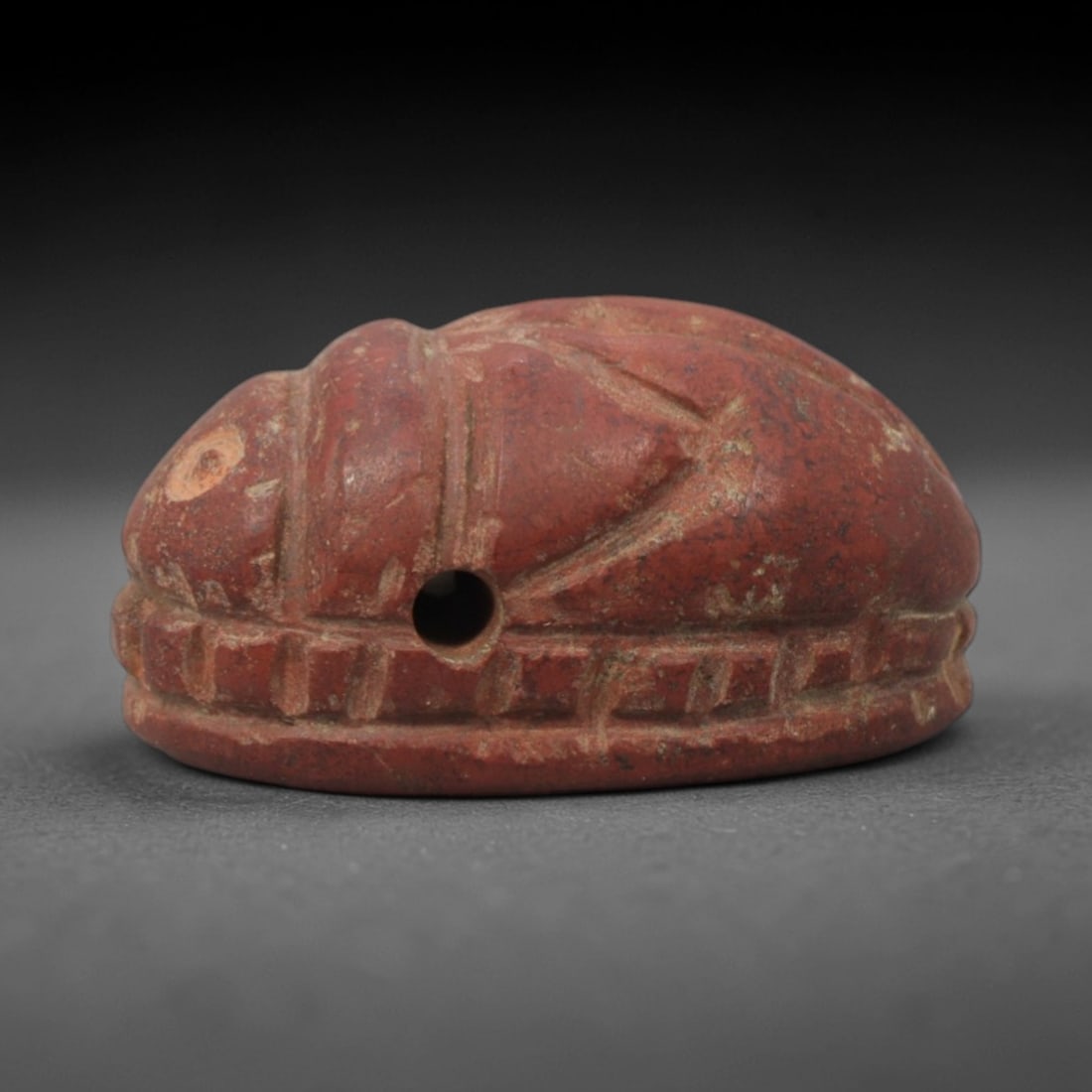 Ancient Egyptian Scarab Amulet - Egyptian Stone Pendant, 83XQ: This amulet is carved from a rich, reddish-brown stone, shaped into the iconic scarab beetle form with a perforated suspension hole through the body, confirming its use as a wearable protective charm.