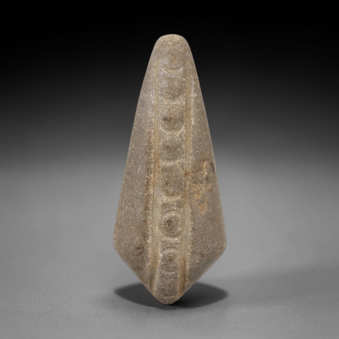 Ancient Egyptian Stone Amulet - Circular Incised Motif, 85AE: Carved from stone, this ancient Egyptian amulet features a series of circular incised motifs arranged in a linear pattern, a design typical of protective amulets from the Late Period (c. 664-332 BCE).
