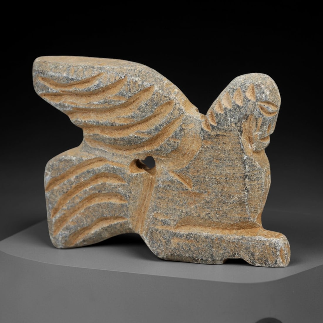 Ancient Schist Lamassu - Miniature Carved Figurine, 47AH: Carved from schist stone, this ancient miniature lamassu figurine features a stylized winged human-headed form with defined facial features and wing detailing. The stone exhibits a natural, earthy pat