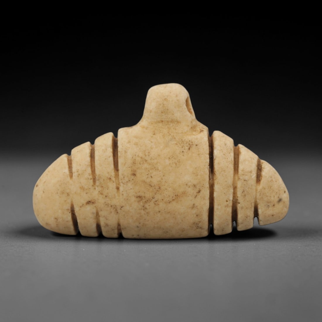 Ancient Stone Bead - Egyptian Amulet Bead, 47XR: Carved from deep reddish-brown stone, this cylindrical bead features horizontal incised ridges encircling its body and a radiating linear pattern above a central axial perforation for threading. The s