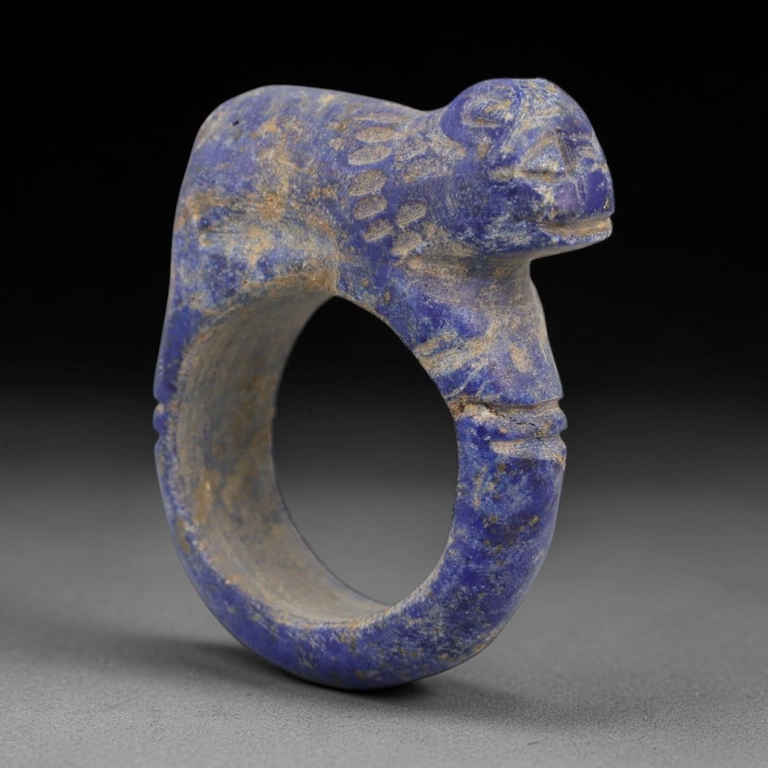 Ancient Lapis Achaemenid Ring - Zoomorphic Carving, 33AH: Carved from lapis lazuli stone, this ancient Achaemenid ring features a zoomorphic feline form with detailed facial features, a stylized mane, and a compact body, characteristic of Achaemenid glyptic