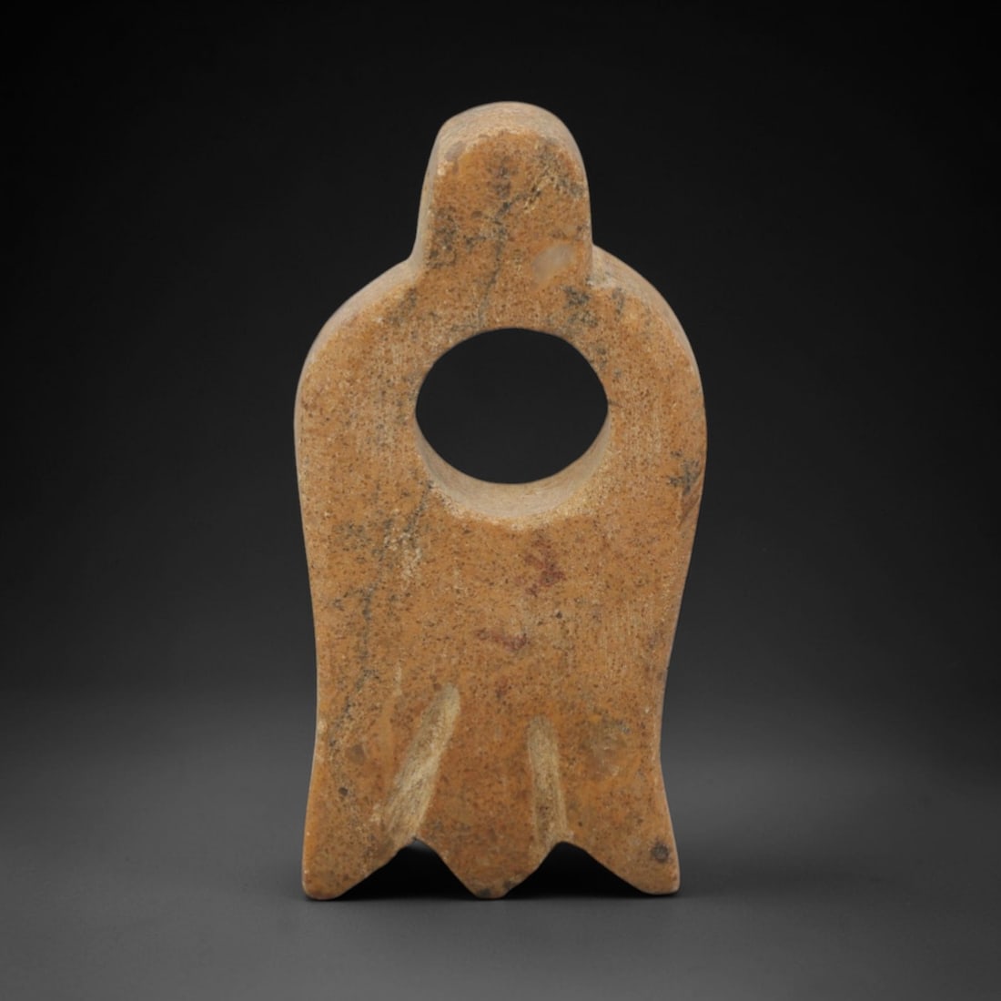 Ancient Stone Tyet Amulet - Egyptian Pendant, 95XQ: Carved from a warm ochre-toned stone, this amulet takes the form of the Egyptian Tyet (or Knot of Isis), featuring a central circular perforation, symmetrical curved upper lobes, and a serrated lower