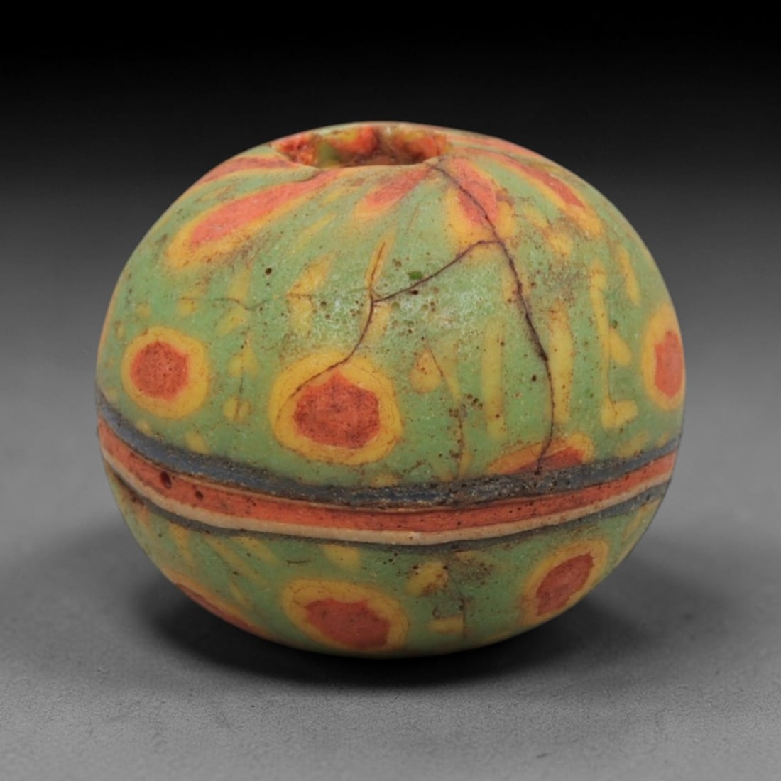 Ancient Islamic Glass Bead - Mosaic Eye Trade Bead, 90ZN: Crafted from ancient glass, this Islamic period bead features a mosaic eye pattern with layered yellow, red, and green glass trails applied to a translucent base, characteristic of decorative glassmak